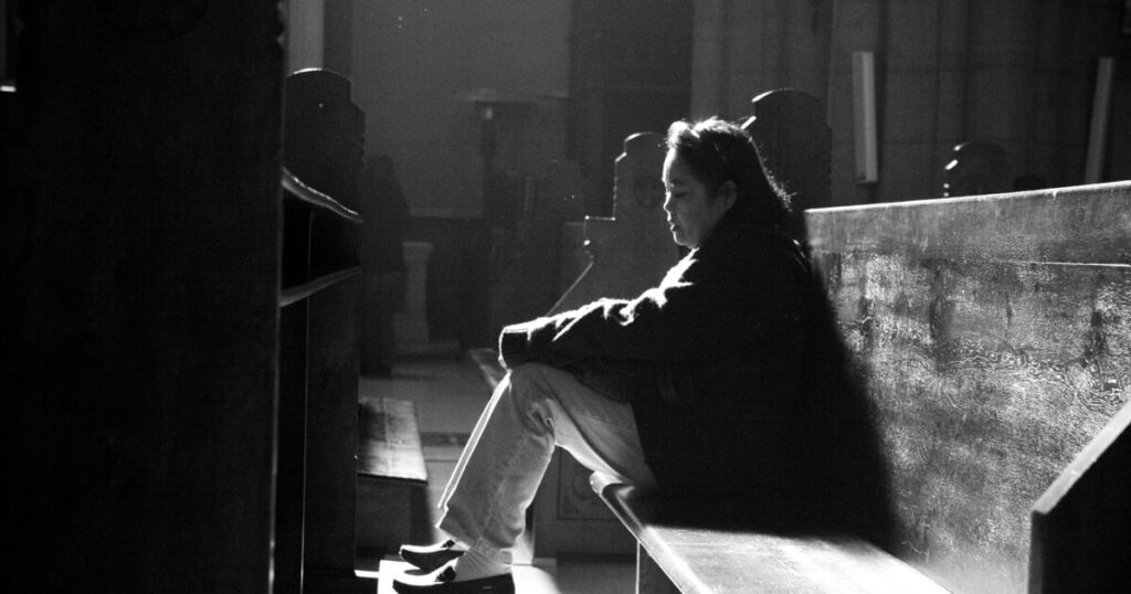 tired and distressed woman sits alone in a pew, a small reminder that abuse impacts the whole chuch