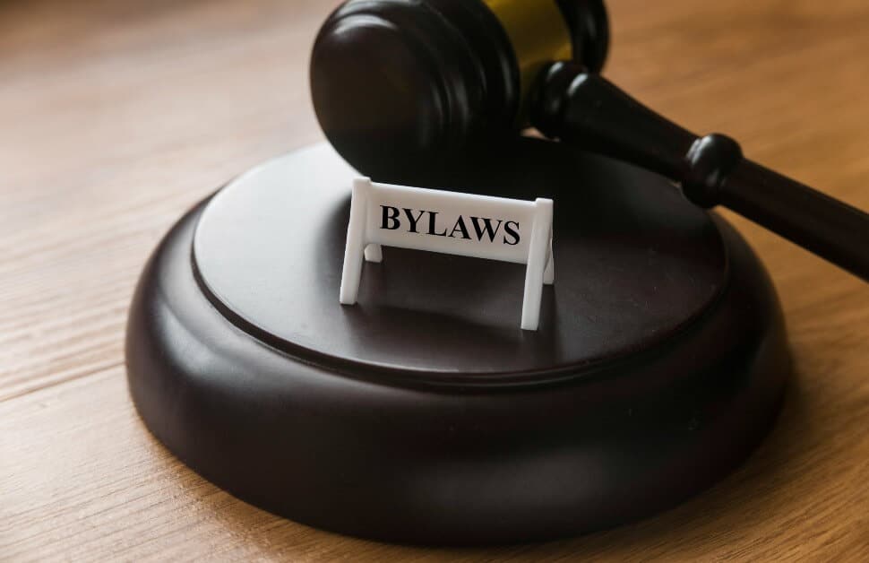 A gold-accented, lacquered maple gavel on a blonde oak desk with a sign that reads "BYLAWS"