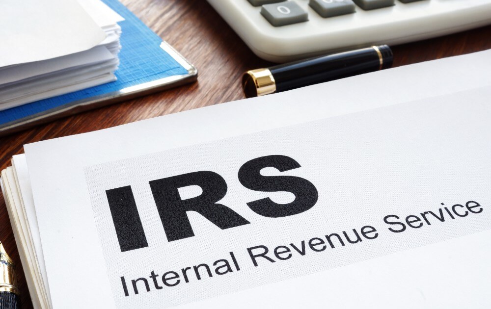 Are church bylaws legally binding? A stack of white papers with the words "IRS Internal Revenue Service" on a desk with a pen and white calculator