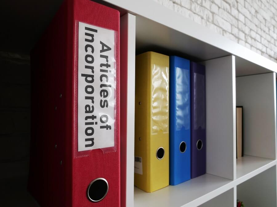 How to start a church legally: red binder in a book shelf with "Articles of Incorporation" labeling on the spine