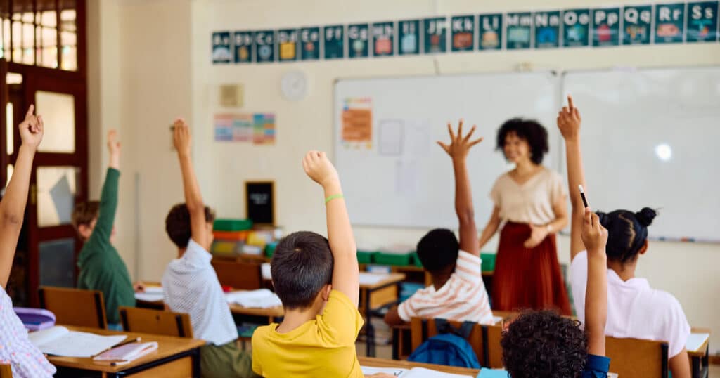 Students raising their hands in a classroom are a reminder that SGO tax credits can ultimately benefit the recipients of SGO scholarships.