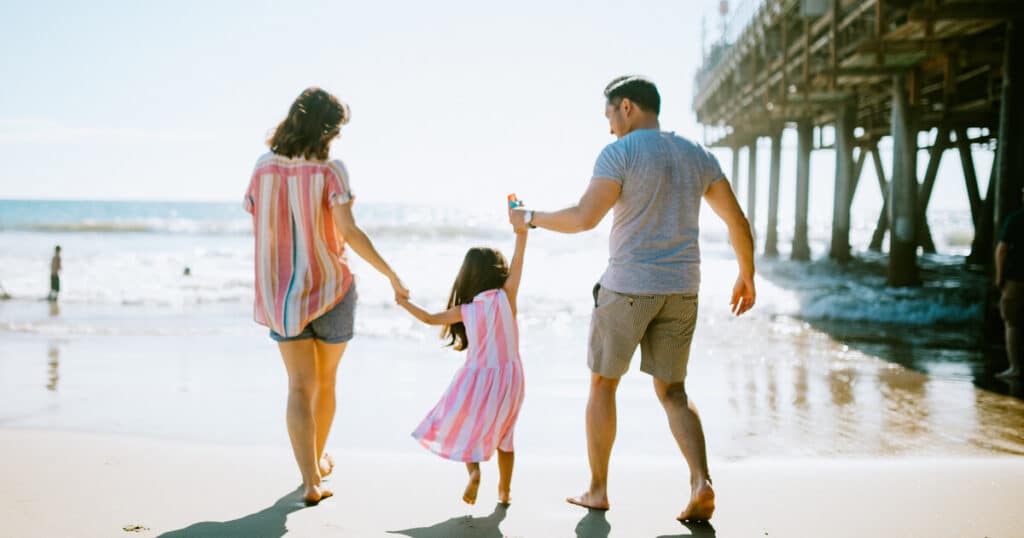 A young family on the beach will protect their loved ones by asking the question, "How much does estate planning cost in California?"