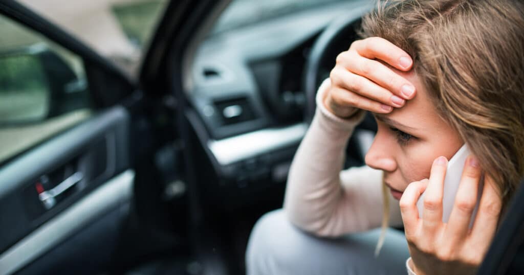 A woman on the phone is concerned because accidents with self driving cars are stressful.