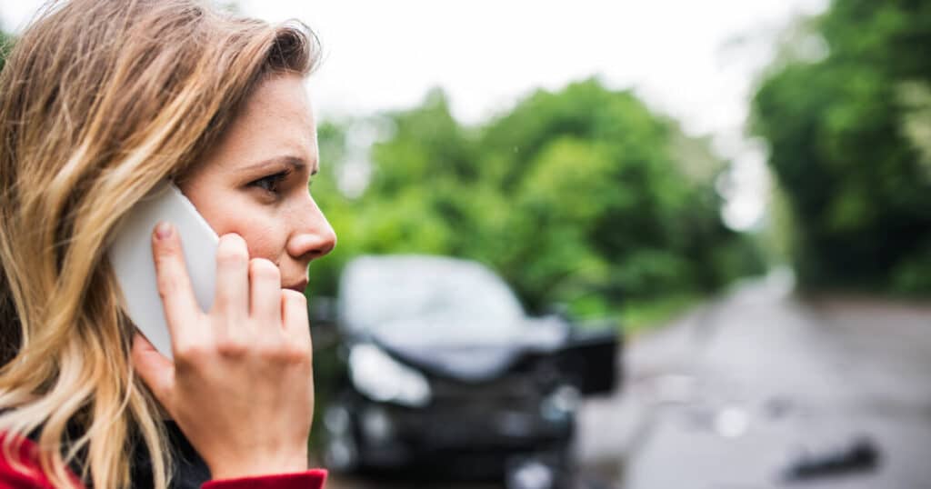 A car accident witness calls 911 at the scene of an accident.