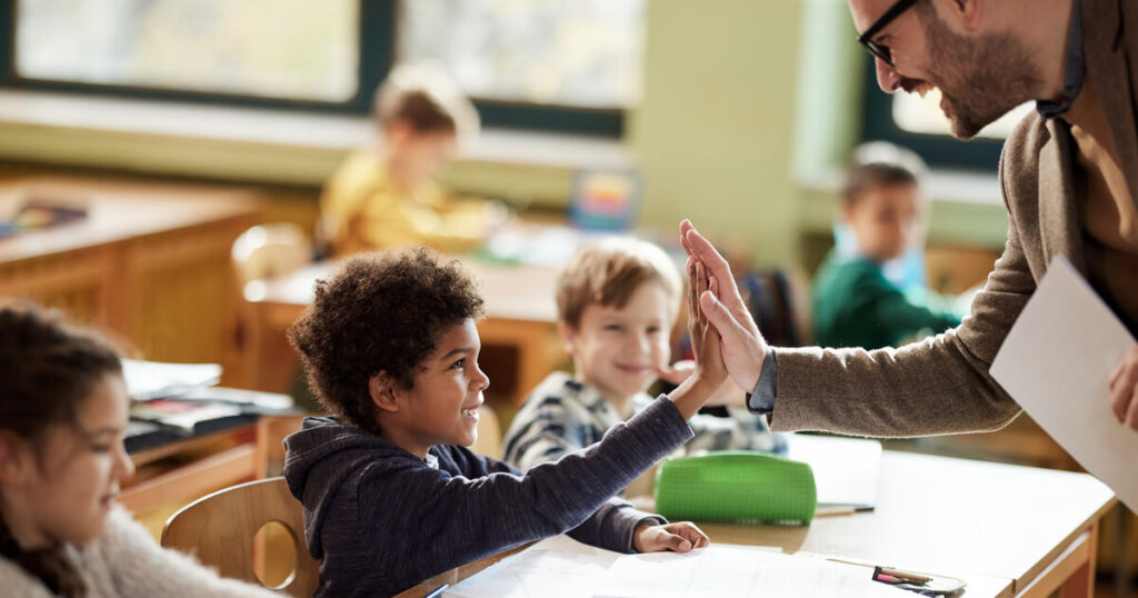 A student high fives his teacher, reminding us that the new federal tax credit is a victory for students in need of educational funding.