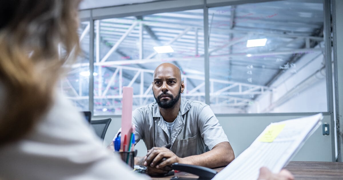 A man who has been injured on the job is having a tense conversation with his boss and wondering, "What happens if I get fired while on workers' comp?"