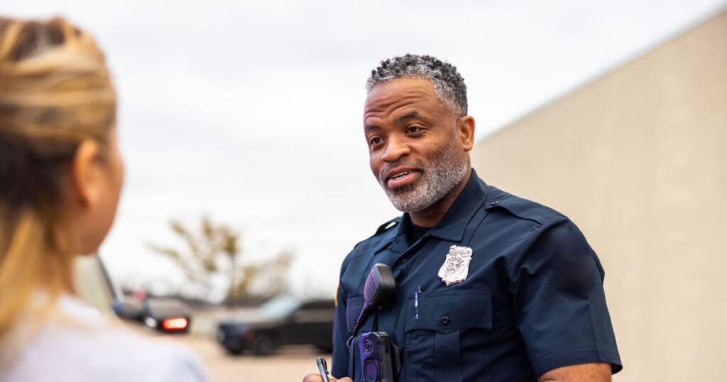 A woman speaks to a police man after a no insurance car accident.